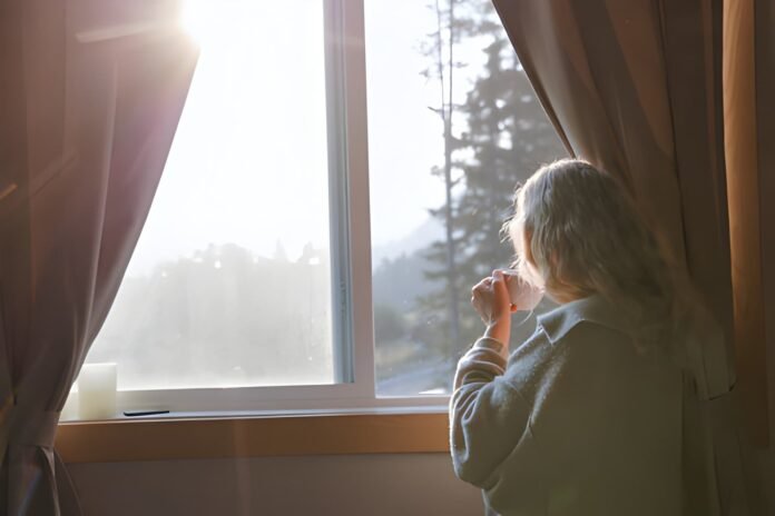 Morning light Person enjoying coffee by a bright window during sunrise.